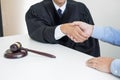 Gavel hammer Justice on wooden table with judge and client shaking hands after adviced in background at courtroom, lawyer service Royalty Free Stock Photo