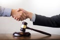 Gavel Justice hammer on wooden table with judge and client shaking hands after adviced in background at courtroom, lawyer service