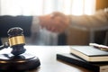 Gavel Justice hammer on wooden table with judge and client shaking hands after adviced in background at courtroom, lawyer service Royalty Free Stock Photo