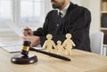 Gavel and little family figures on table in courtroom, with judge sitting in background Royalty Free Stock Photo