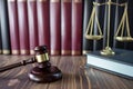 gavel beside scales of justice on wooden table, law books background Royalty Free Stock Photo