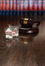 Gavel and Small Model House on Wooden Table Royalty Free Stock Photo