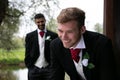 Gay couple of grooms pose for photographs by a lake on their wedding day