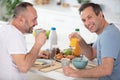 gay couple have breakfast in kitchen in sunny day