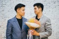 Gay couple holding a bouquet of flowers, ready to give to his partner for special occasions or wedding proposal.