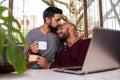 Gay couple moment, enjoying a cup of coffee, kiss the forehead in the couch Royalty Free Stock Photo