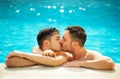 Gay couple relaxing in swimming pool. LGBT. Two young men enjoying nature outdoors, kissing and hugging Royalty Free Stock Photo