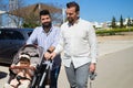 Gay couple and their young daughter taking a walk in the park. The little daughter is riding in the carriage