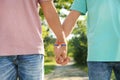 Gay couple with wristbands holding hands outdoors