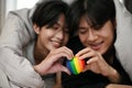 Gay couples lying on bed under the blanket and holding a rainbow LGBT heart symbol together Royalty Free Stock Photo