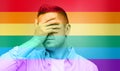 Gay covering his face by hand over rainbow flag Royalty Free Stock Photo