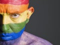 Gay flag painted face man, serious expression. Royalty Free Stock Photo