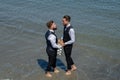 Gay grooms walking together on sea beach during Wedding day. Romantic men in sea water. Romantic and sensual gay couple Royalty Free Stock Photo