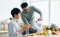 Gay LGBT sweet Asian couple wearing pajamas, smiling, with happiness and love while making and pouring juice smoothie to glass and Royalty Free Stock Photo