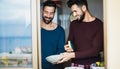 Gay male couple washing dishes together inside home kitchen - Focus on right man Royalty Free Stock Photo