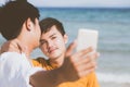 Gay portrait young couple smiling taking a selfie photo together with smart mobile phone at beach Royalty Free Stock Photo