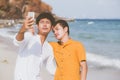 Gay portrait young couple smiling taking a selfie photo together with smart mobile phone at beach Royalty Free Stock Photo