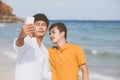 Gay portrait young couple smiling taking a selfie photo together with smart mobile phone at beach Royalty Free Stock Photo