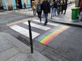 Gay pride flag crosswalk in Paris gay village with people crossing. Legs, france. Royalty Free Stock Photo