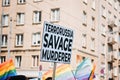 Gay pride, LGBTQ solidarity march with rainbow flags and antiwar posters. Hands holding a poster with antiwar posters