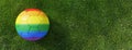 Gay pride rainbow color soccer ball on grass field, overhead. LGBT football sport event. 3d render