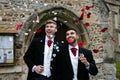 Gay wedding, grooms leave village church after being married to smiles and confetti Royalty Free Stock Photo