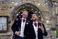 Gay wedding, grooms leave village church after being married to smiles and confetti Royalty Free Stock Photo