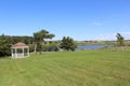 A gazebo and grassy lawn next to a lake and a horse pasture near the childhood home of Lucy Maud Montgomery author of Anne novels