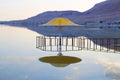 The gazebo for protection from the sun reflected in Dead Sea water at sunset