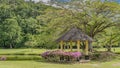 A gazebo for relaxing is set in a tropical garden next to the lake. Royalty Free Stock Photo