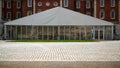 gazebo or shed or temporary structure on flat cobbled ground with red brick building in background