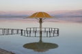 Gazebo for sun protection reflected in Dead Sea water at sunset