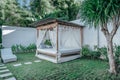 Gazebo with a wooden bed under a mosquito grid on a outside