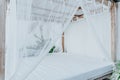 Gazebo with a wooden bed under a mosquito grid on a outside