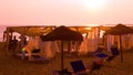 Gazebos and straw umbrellas on the beach at sunset