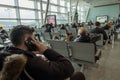 A lot of people sitting on airport seats and one man talking to phone before getting in the plane in Aydin Menderes Airport