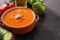 Gazpacho soup in crockpot and ingredients on black slate background. Copy space