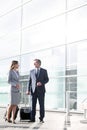 Businessman talking to businesswoman in airport departure area Royalty Free Stock Photo