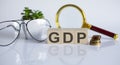 GDP concept on wooden cubes and flower ,glasses ,coins and magnifier on white background Royalty Free Stock Photo