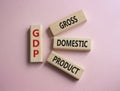 GDP - Gross domestic product symbol. Concept word GDP on wooden blocks. Beautiful pink background. Business and GDP concept. Copy