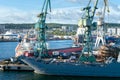 Gdynia, Poland - 09.23.2021: Port cranes loading docked cargo ship on a sunny day.