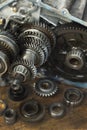 Gear wheels, damaged modes lie on a wooden table top. In the background a manual transmission from the car. Royalty Free Stock Photo