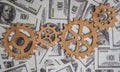 Gears made of wood on the background of dollar bills.