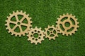 Gears of natural wood on a background of green grass symbolize green technology.