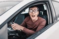 geek driver is staring at the camera and holding the steering wheel. Concept of a novice driver and learning to drive Royalty Free Stock Photo