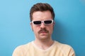 Geek retro caucasian man with funny mustache sunglasses with serious emotion on face
