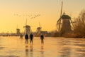 Ice skater on a frozen windmill canal at sunrise moment