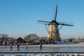 Ice skater on a frozen windmill canal at sunrise moment