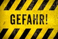 GEFAHR! in German, danger warning sign text with yellow and black stripes painted over concrete wall cement texture background