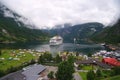 Geiranger, Norway - January 25, 2010: vacation, trip, wanderlust. Ship in norwegian fjord on cloudy sky. Ocean liner in village ha Royalty Free Stock Photo